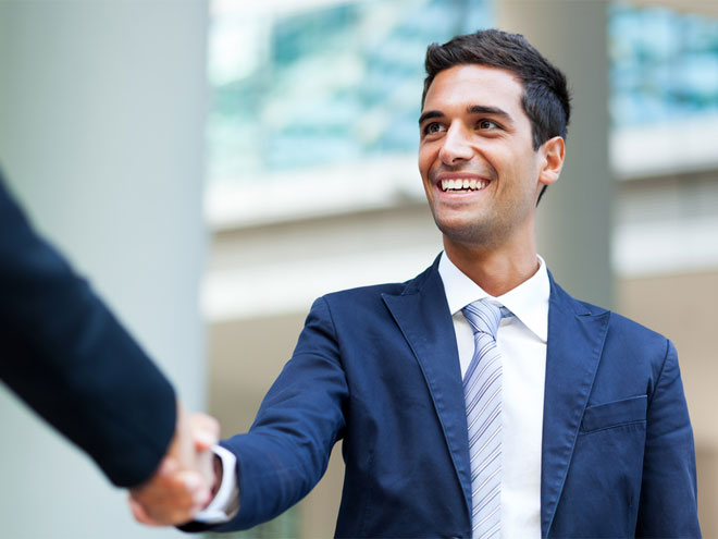 Man in suit smiling and shaking a hand