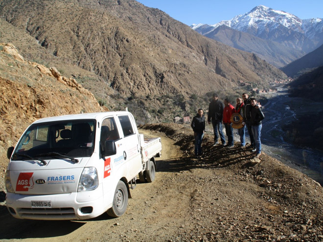 Ags minivan with people posing with mountains at the back