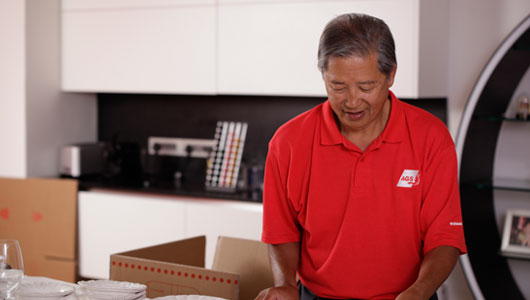 AGS Movers staff member busy packing items into boxes for moving.