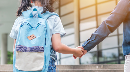 Kid with backpack held by hand